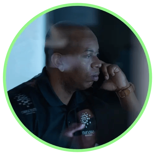 Manawa team member using phone looking at computer screen