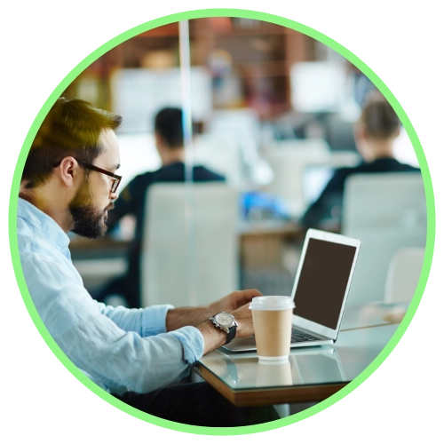 Businessman working on laptop in crowded office